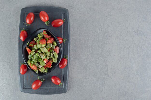 Ensalada de frijoles y tomate cherry rojo sobre una tabla de madera negra