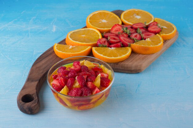 Ensalada de frutas con fresas y naranjas con tabla de frutas a un lado