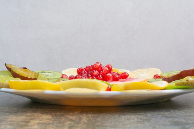Ensalada de frutas con granada, pomelo y kiwi en plato blanco. Foto de alta calidad