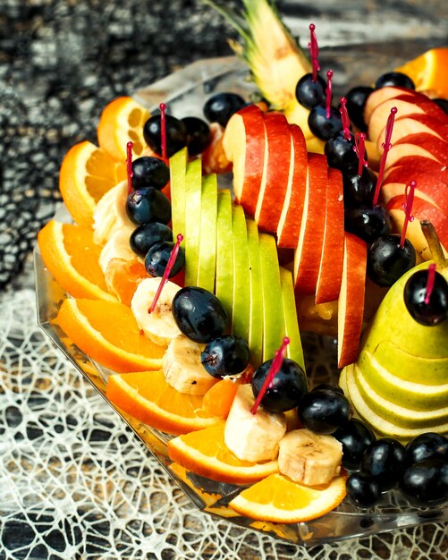 Ensalada de frutas con manzanas, naranjas, plátanos, uvas y peras.