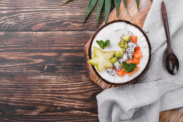 Ensalada de frutas en plato de coco en mesa de madera