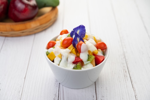 Ensalada de frutas en un recipiente en el piso de madera.