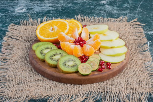 Ensalada de frutas en rodajas y picadas en un plato sobre la superficie azul.