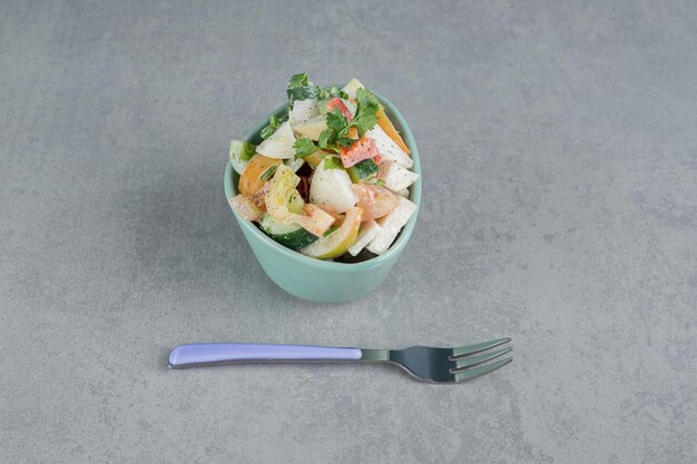 Ensalada de frutas en una taza azul con aceitunas negras.