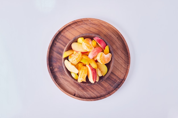 Ensalada de frutas de temporada en una taza de madera, vista superior.