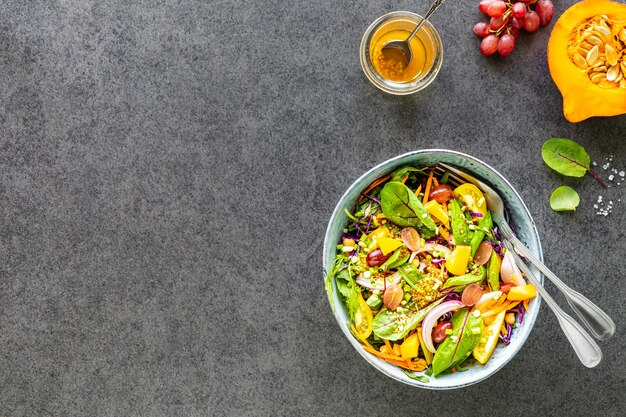 Ensalada de frutas y verduras frescas en un plato sobre una mesa de piedra negra. Vista superior