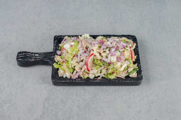 Ensalada de frutas y verduras picadas sobre una tabla de madera.