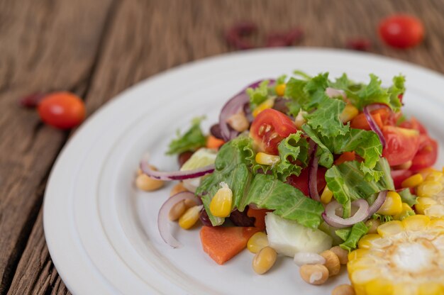 Ensalada de frutas y verduras en un plato blanco sobre un piso de madera