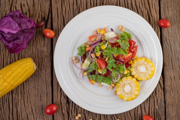 Ensalada de frutas y verduras en un plato blanco sobre un piso de madera