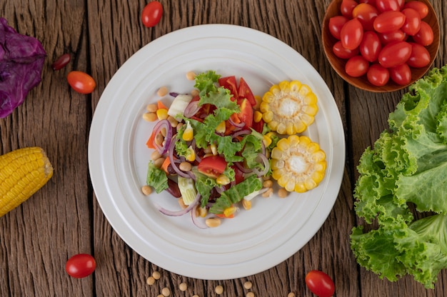 Foto gratuita ensalada de frutas y verduras en un plato blanco sobre un piso de madera