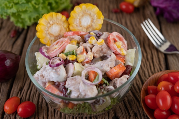 Ensalada de frutas y verduras en un vaso de vidrio sobre un piso de madera