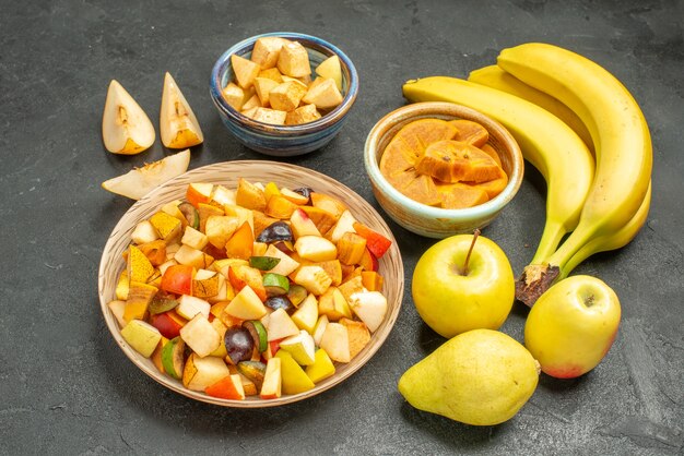 Ensalada de frutas vista frontal con frutas frescas en rodajas en la mesa de color gris oscuro fruta fresca del árbol