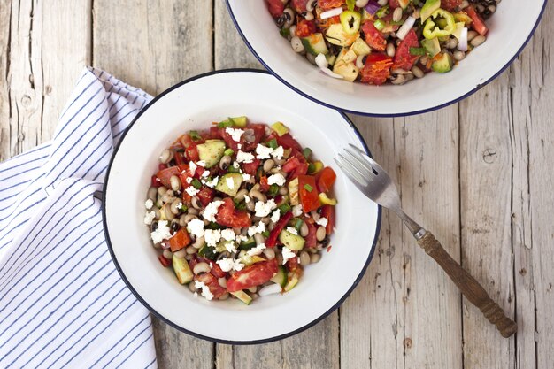 Ensalada griega en platos con un tenedor y una servilleta rayada al lado