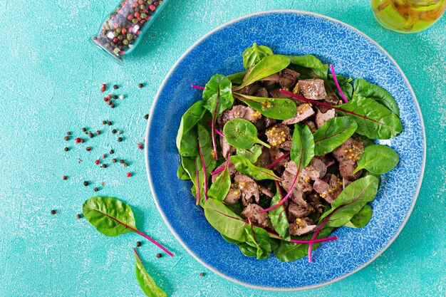 Ensalada de hígado de pollo y hojas de espinacas y acelgas. Vista superior plana