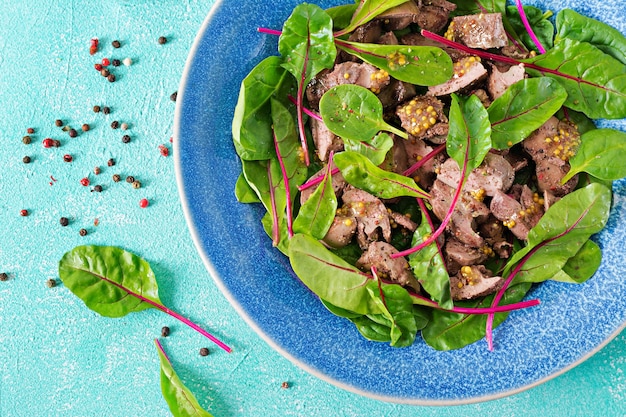 Ensalada de hígado de pollo y hojas de espinacas y acelgas. Vista superior plana