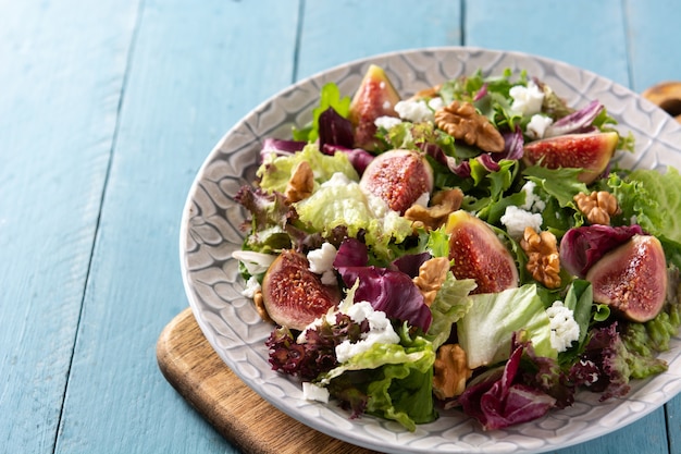 Foto gratuita ensalada de higos con queso y nueces sobre mesa de madera azul