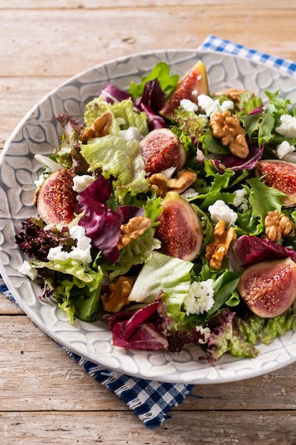 Ensalada de higos con queso y nueces sobre mesa de madera.