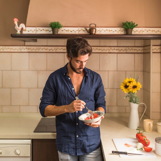 Foto gratuita ensalada de hombre comiendo en el cuenco