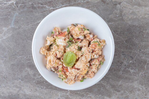 Ensalada de huevo frito en un tazón blanco.