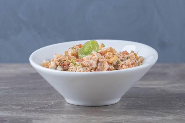 Ensalada de huevo frito en un tazón blanco.