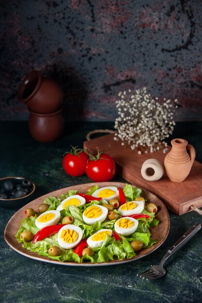 Ensalada de huevo vista frontal se compone de aceitunas y ensalada verde sobre fondo azul oscuro