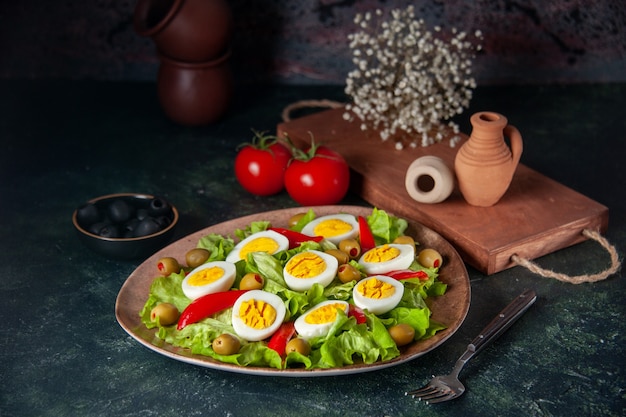 Ensalada de huevo vista frontal se compone de aceitunas y ensalada verde sobre fondo azul oscuro