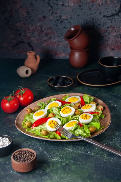 Ensalada de huevo vista frontal se compone de aceitunas y ensalada verde sobre fondo oscuro