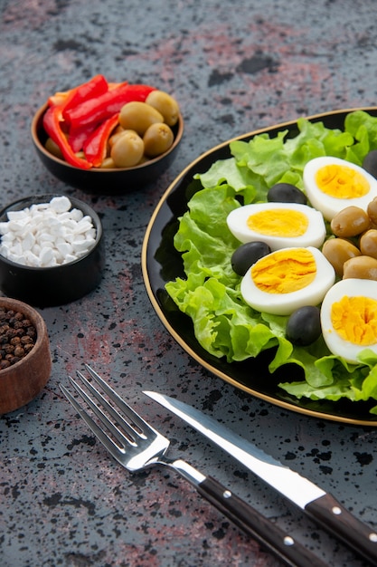 Ensalada de huevo vista frontal consiste en ensalada verde y aceitunas sobre fondo claro