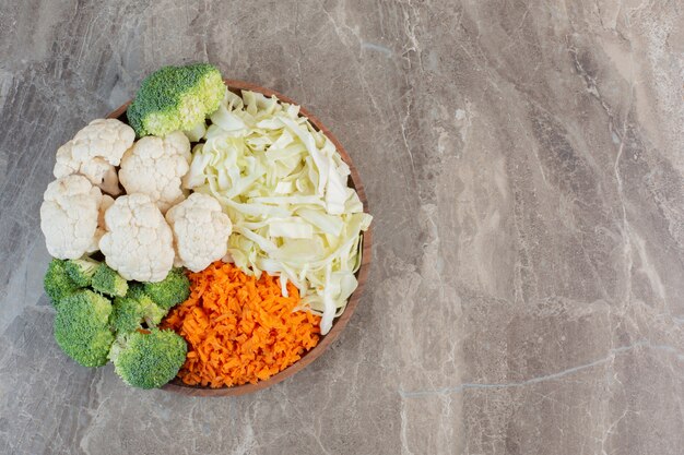 Ensalada de ingredientes frescos y apetitosos preparados y exhibidos en una bandeja de madera sobre mármol.