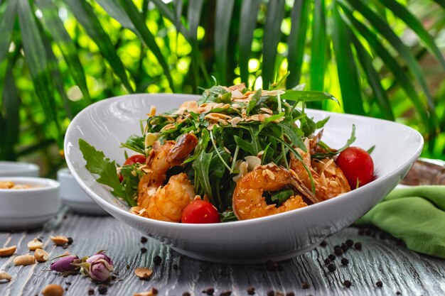 Ensalada de langostinos tomate rúcula salsa de maní vista lateral