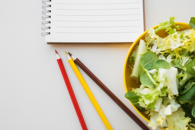 Foto gratuita ensalada y lápices cerca del cuaderno