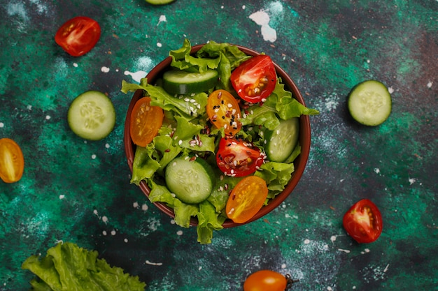 Ensalada de lechuga fresca con tomates amarillos, rodajas, tomates cherry, tazón de semillas en la oscuridad,