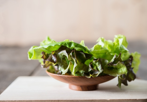 Ensalada de lechuga verde fresca en plato de madera.