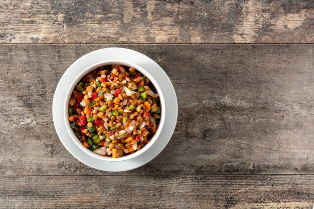 Ensalada de lentejas con peppersonion y zanahoria en un bol sobre mesa de madera