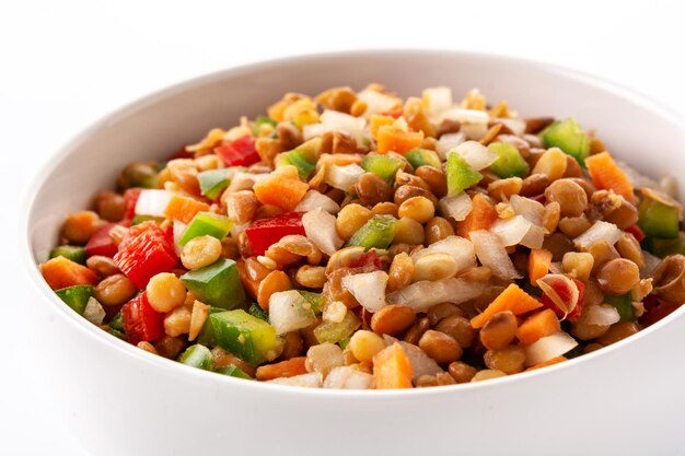 Ensalada de lentejas con peppersonion y zanahoria en un recipiente aislado sobre fondo blanco.