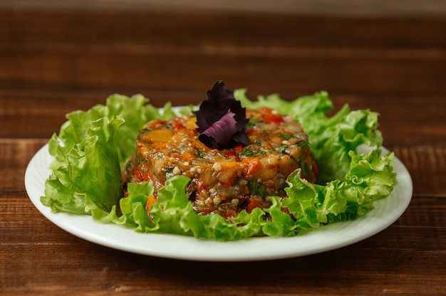 Ensalada de mangal hecha de verduras a la parrilla y servida con hojas rojas de basílica en la parte superior