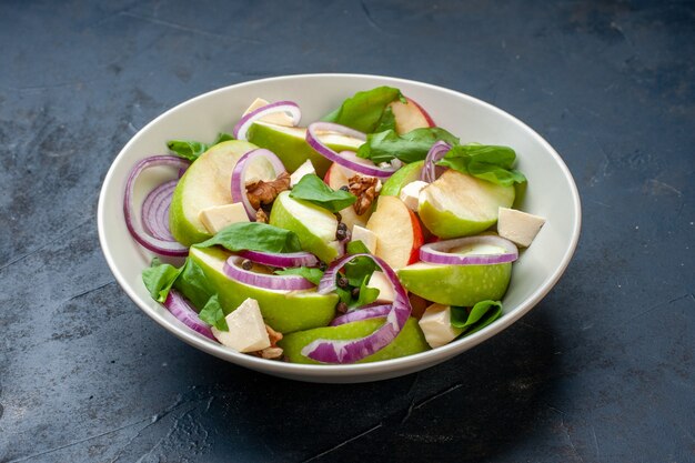 Ensalada de manzana fresca vista inferior en un tazón en el cuadro azul oscuro