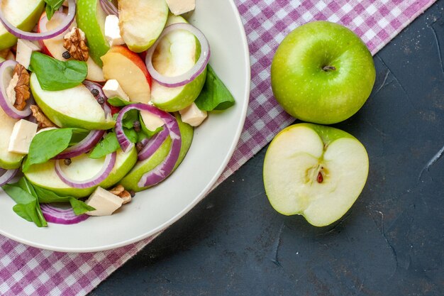 Ensalada de manzana fresca vista superior en plato redondo mantel a cuadros morado y blanco de manzana en mesa oscura