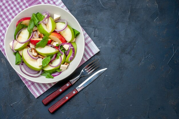 Ensalada de manzana fresca vista superior en plato redondo mantel a cuadros morado y blanco sobre mesa oscura