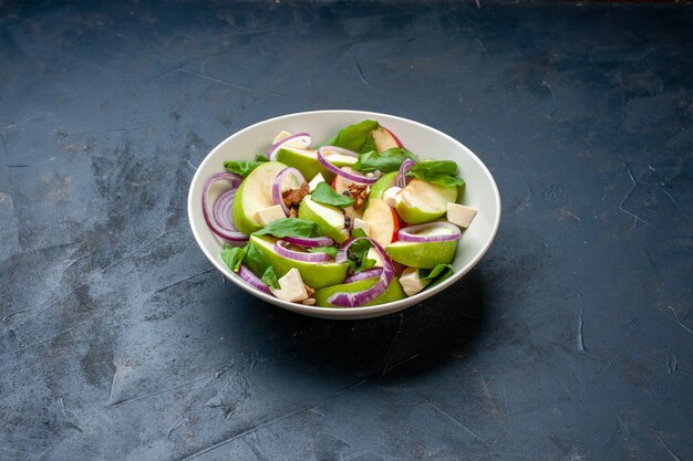 Ensalada de manzana verde de vista inferior en un tazón en la mesa azul oscuro con lugar libre