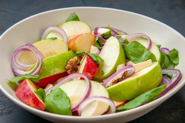 Ensalada de manzana de vista inferior con cebolla y otros alimentos en un plato hondo en la mesa oscura fod