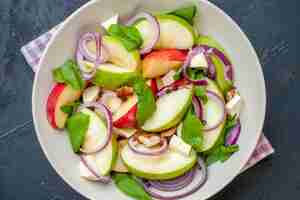 Foto gratuita ensalada de manzana de vista superior cercana en tazón de fuente servilleta a cuadros púrpura y blanco sobre mesa oscura