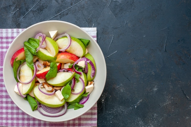 Foto gratuita ensalada de manzana vista superior en tazón de fuente servilleta a cuadros púrpura y blanco sobre mesa oscura con lugar de copia