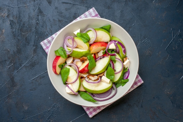 Ensalada de manzana vista superior en tazón de fuente servilleta a cuadros púrpura y blanco sobre mesa oscura