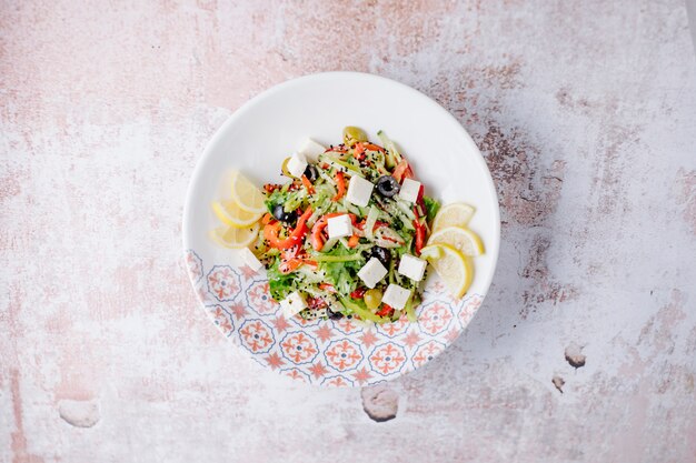 Ensalada mixta de verduras con cubitos de queso blanco y rodajas de limón.