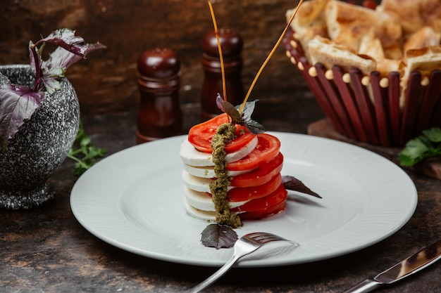 Ensalada con mozarella y rodajas de tomate con aderezo basilico y herbal.