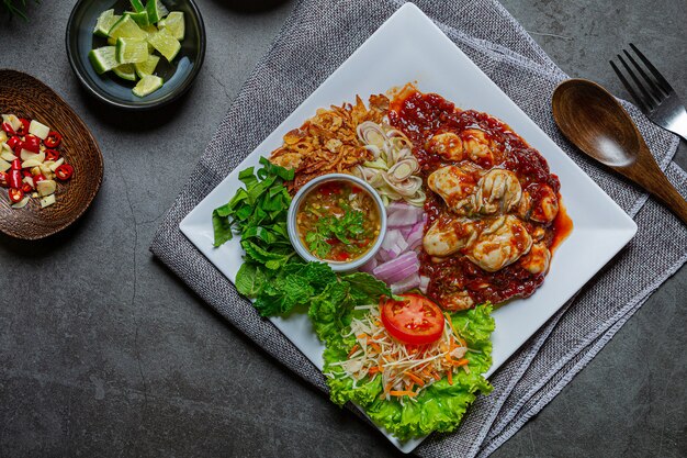 Ensalada de ostras frescas picantes e ingredientes alimentarios tailandeses.