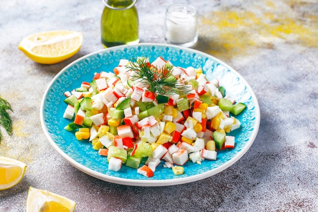 Foto gratuita ensalada con palitos de cangrejo, huevos, maíz y pepino.