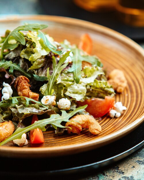 ensalada de palomitas de maíz con rúcula camarones fritos palomitas de maíz y tomates en un plato