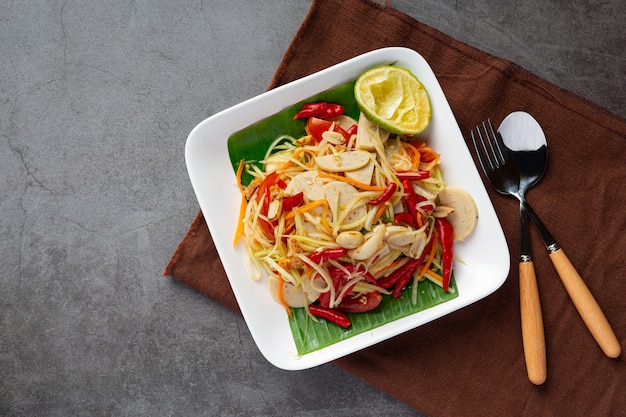 Ensalada de papaya servida con fideos de arroz y ensalada de verduras Decorada con ingredientes de la comida tailandesa.